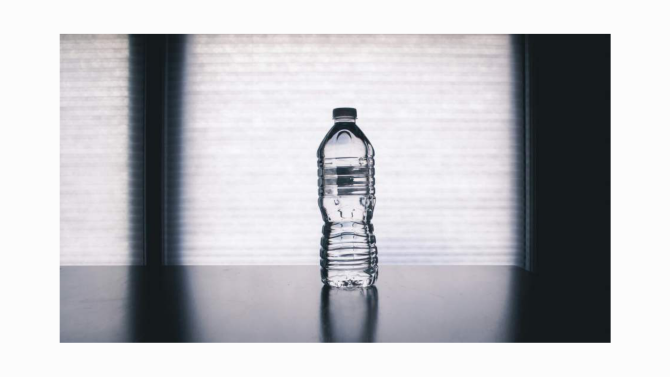 A clear bottle with a lid and a little water line
